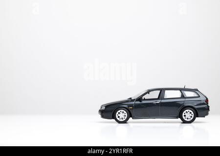 Small metal toy model car isolated on white. Close up shot, side profile, dark gray station wagon, no people. Stock Photo