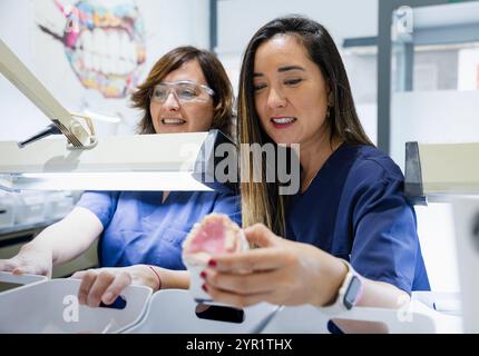 Two female dental technicians working on a dental prosthetic model together. Stock Photo