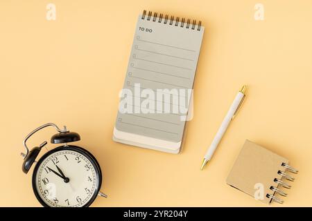 To do list in spiral notepad., retro alarm clock and white pen. Trendy pastel background, flat lay style. Planning concept. Stock Photo