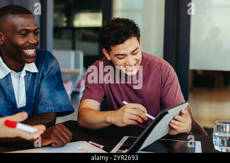 College students using technology for collaborative learning, engaging in a productive study session with a digital tablet in a modern educational set Stock Photo