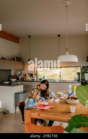 High angle view of mother assisting son doing homework while sitting near table at home Stock Photo