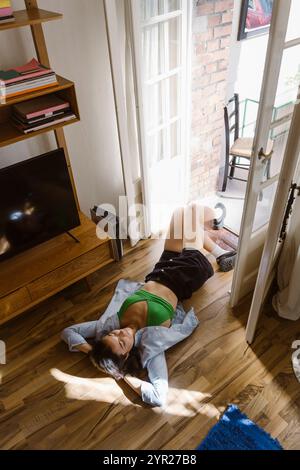 High angle view of woman lying down on hardwood floor at home Stock Photo
