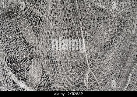 Gray fishing net made of knotted ropes and cords in close-up Stock Photo