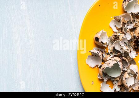 Quail eggshells on a yellow plate. Top view, close-up. High quality photo Stock Photo