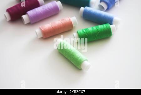 Many colorful sewing threads on light background. Stock Photo