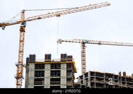 A bustling construction site featuring cranes towering above, with a large building currently undergoing construction and development Stock Photo