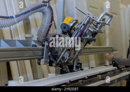 Woodworking machine in factory, showing an automated cutting drilling tool used for door with hose attached, for dust extraction machine is positioned Stock Photo