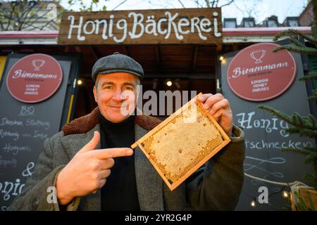 Dresden, Germany. 02nd Dec, 2024. Beekeeper Rico Heinzig holds a honeycomb in his hands at his stand at the historic Christmas market on Neumarkt. Credit: Robert Michael/dpa/Alamy Live News Stock Photo