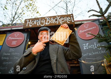 Dresden, Germany. 02nd Dec, 2024. Beekeeper Rico Heinzig holds a honeycomb in his hands at his stand at the historic Christmas market on Neumarkt. Credit: Robert Michael/dpa/Alamy Live News Stock Photo