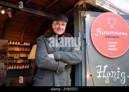 Dresden, Germany. 02nd Dec, 2024. Beekeeper Rico Heinzig stands at his stall at the historic Christmas market on Neumarkt. Credit: Robert Michael/dpa/Alamy Live News Stock Photo