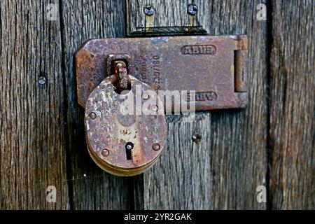 rusty padlock on rough wooden door Stock Photo