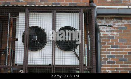 the outside of the industrial air conditioner in the enclosure on the wall of the building, the fans of the air conditioning system outside Stock Photo