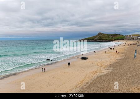 Porthmeor beach at dusk on an autumnal day with a few hardy surfers in the sea St Ives Cornwall England Stock Photo
