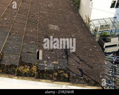 Close-up aerial view of a roof showing a loose roofing tile and a gap where water can come in Stock Photo