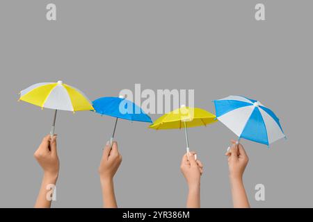 Female hands with different mini umbrellas on grey background Stock Photo