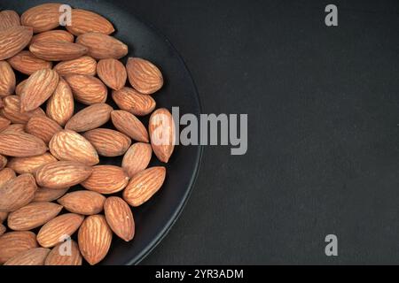 Showing half plate of almonds in black background Stock Photo
