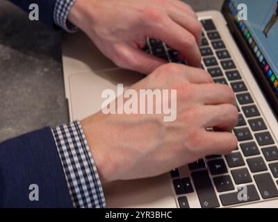 Businessmans hands typing on laptop keyboard, focused on 3d modeling project in modern office environment Stock Photo