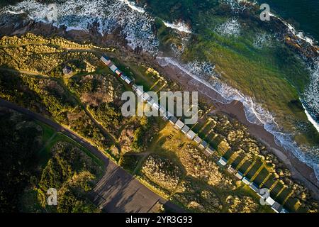 Hopeman Moray Coast Scotland the sea breaking on rocks and sand beach a row of beach huts or chalets and the pavilion in winter sunshine Stock Photo