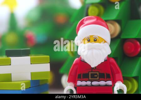 Tambov, Russian Federation - December 02, 2024 A Lego Santa Claus minifigure standing in front of a Christmas tree and a stack of gift boxes. Close up Stock Photo