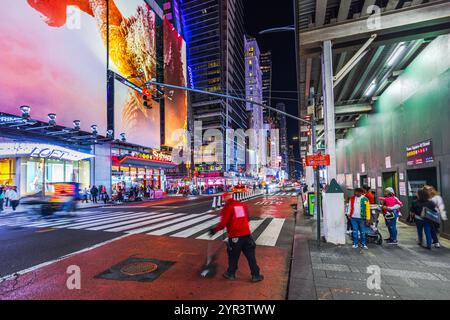 Times Square with night featuring vibrant billboards, a street cleaner in motion blur and bustling city life with pedestrians. New York. USA. Stock Photo