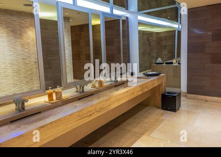 Modern restroom interior featuring sleek marble countertop with multiple sinks and mirrors. Mexico. Stock Photo