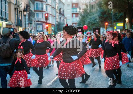 The image shows a group of people participating in what appears to be a street parade or festival. They are dressed in matching costumes featuring red Stock Photo