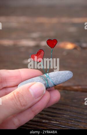 Wire-Wrapped Stone with Red Hearts from resin. Handmade Valentine’s Ornament on Natural Stone Stock Photo