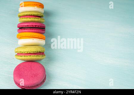 Multi-colored macaroons are stacked. Cherry, pistachio and mango macaroons on a light blue background. Copyspace, Place for text. High quality photo Stock Photo