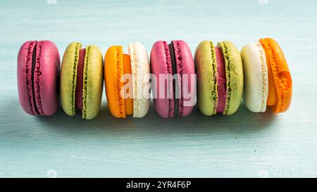 Multi-colored macaroons are stacked. Cherry, pistachio and mango macaroons on a light blue background. Copyspace, Place for text. High quality photo Stock Photo
