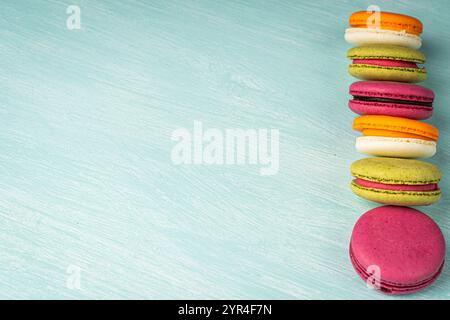 Multi-colored macaroons are stacked. Cherry, pistachio and mango macaroons on a light blue background. Copyspace, Place for text. High quality photo Stock Photo