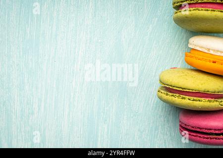 Multi-colored macaroons are stacked. Cherry, pistachio and mango macaroons on a light blue background. Copyspace, Place for text. High quality photo Stock Photo
