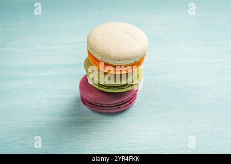 Multi-colored macaroons are stacked. Cherry, pistachio and mango macaroons on a light blue background. Copyspace, Place for text. High quality photo Stock Photo