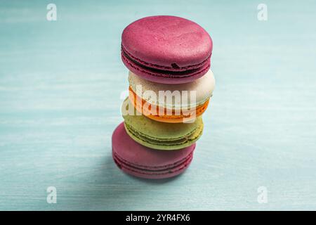 Multi-colored macaroons are stacked. Cherry, pistachio and mango macaroons on a light blue background. Copyspace, Place for text. High quality photo Stock Photo