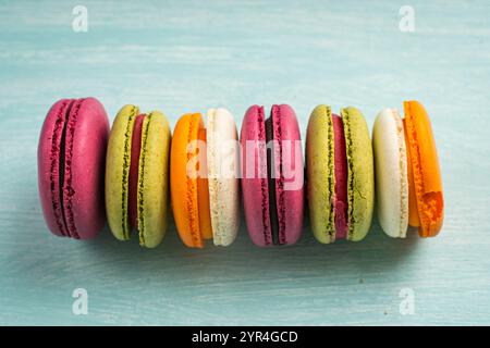 Multi-colored macaroons are stacked. Cherry, pistachio and mango macaroons on a light blue background. Copyspace, Place for text. High quality photo Stock Photo