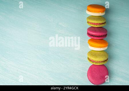 Multi-colored macaroons are stacked. Cherry, pistachio and mango macaroons on a light blue background. Copyspace, Place for text. High quality photo Stock Photo
