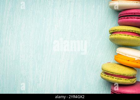 Multi-colored macaroons are stacked. Cherry, pistachio and mango macaroons on a light blue background. Copyspace, Place for text. High quality photo Stock Photo