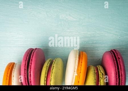 Multi-colored macaroons are stacked. Cherry, pistachio and mango macaroons on a light blue background. Copyspace, Place for text. High quality photo Stock Photo