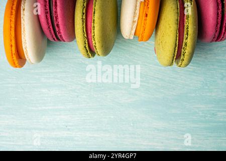 Multi-colored macaroons are stacked. Cherry, pistachio and mango macaroons on a light blue background. Copyspace, Place for text. High quality photo Stock Photo