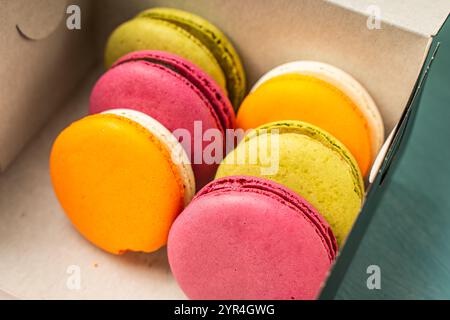 Colorful macaroons in a cardboard box. Packaged cherry, pistachio and mango macarons. High quality photo Stock Photo