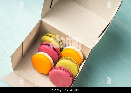 Colorful macaroons in a cardboard box. Packaged cherry, pistachio and mango macarons. High quality photo Stock Photo