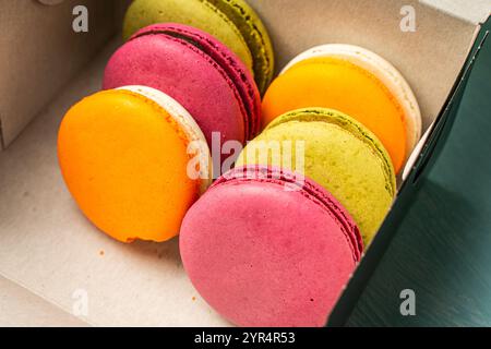 Colorful macaroons in a cardboard box. Packaged cherry, pistachio and mango macarons. High quality photo Stock Photo