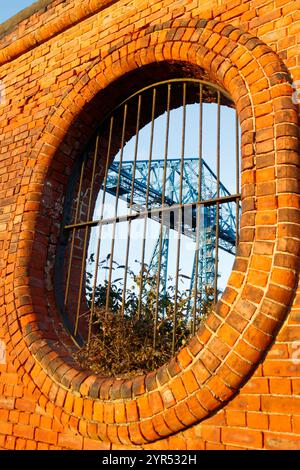 old red brick wall vulcan salt works with circular openings & large blue transporter bridge visible in the background middlesbrough Teesside Uk Stock Photo