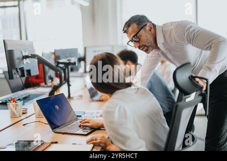 Business professionals collaborating and discussing work at office desk Stock Photo