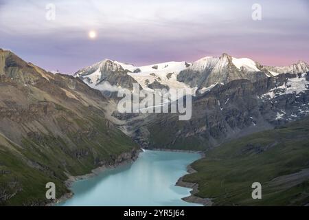 Mountain landscape with turquoise blue reservoir Lac des Dix and summit Mont Blanc de Cheilon, moon above mountain peaks at sunset, Hermenence, Vala Stock Photo