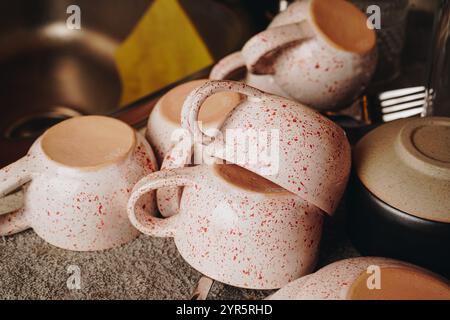 A stack of cups on the table. Cups of different colors and sizes. Plates are stacked on top of each other. The scene evokes a sense of disorder and Stock Photo