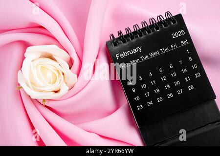 February 2025 desk calendar black color and rose on pink textile