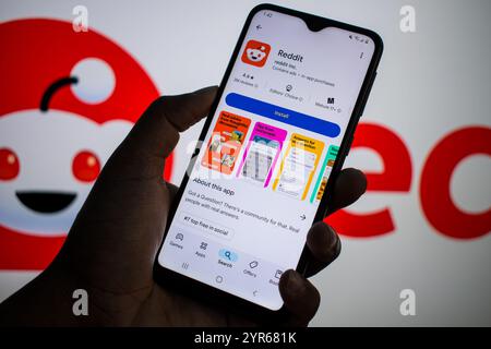SEATTLE, WA, USA - APR 3, 2025: A man holds smartphone with Reddit app on Google Play. Reddit is an American proprietary social news aggregation. Stock Photo