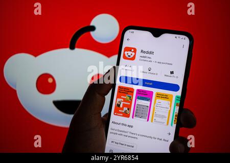 SEATTLE, WA, USA - APR 3, 2025: A man holds smartphone with Reddit app on Google Play. Reddit is an American proprietary social news aggregation. Stock Photo