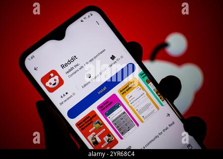 SEATTLE, WA, USA - APR 3, 2025: A man holds smartphone with Reddit app on Google Play. Reddit is an American proprietary social news aggregation. Stock Photo