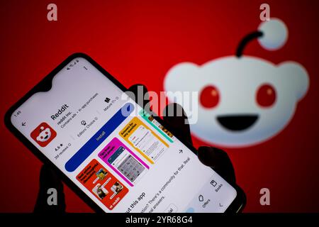 SEATTLE, WA, USA - APR 3, 2025: A man holds smartphone with Reddit app on Google Play. Reddit is an American proprietary social news aggregation. Stock Photo